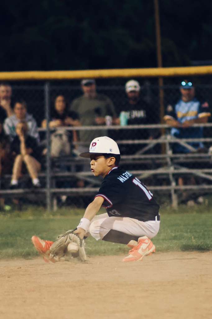Infielder fielding a grounder under the lights